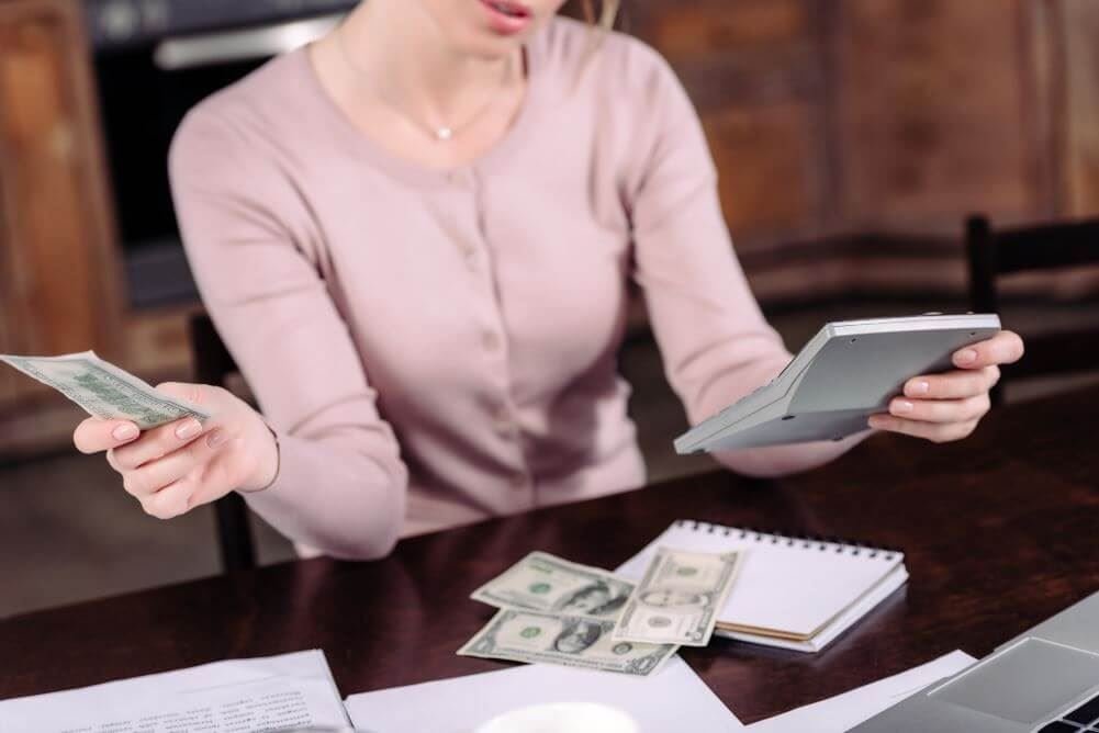 Woman holding cash and a calculator